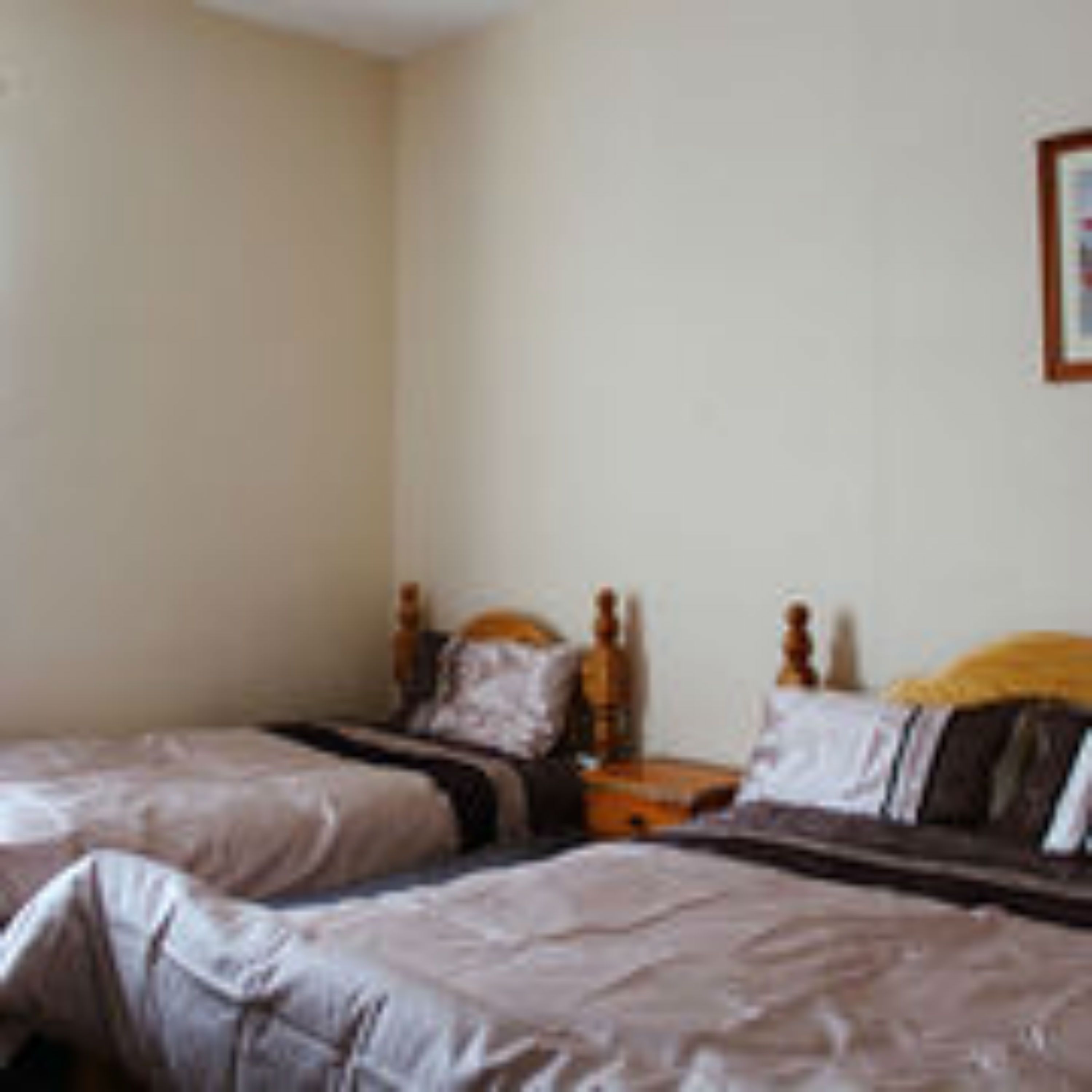 A bedroom with two single beds, a wooden headboard, and a nightstand with a lamp.