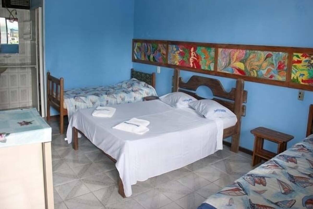 A room with two beds, a small table, and a wall with colorful artwork.