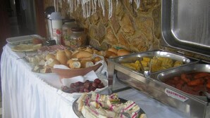 A buffet table with various food items including sandwiches, fruits, and a cake. - Pousada Recanto de Minas (Porto Seguro)