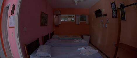 A room with two beds, a ceiling fan, a window with curtains, and a door.