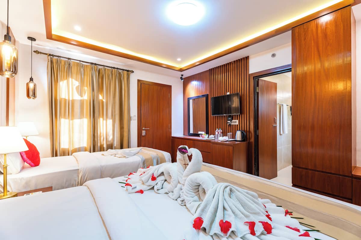 Ein Hotelzimmer mit zwei Betten, einem Fernseher, Holzvertäfelung und einem Spiegel.