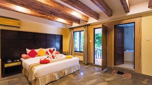 A hotel room with a large bed, a dark headboard, a wooden ceiling, and a view of the outdoors through a glass door. - Hotel Seven Limited (Sauraha)