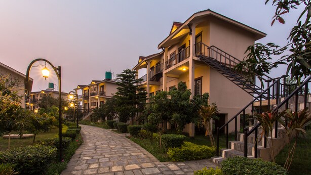 A pathway leading to a building with multiple balconies and a staircase. - Hotel Seven Limited (Sauraha)