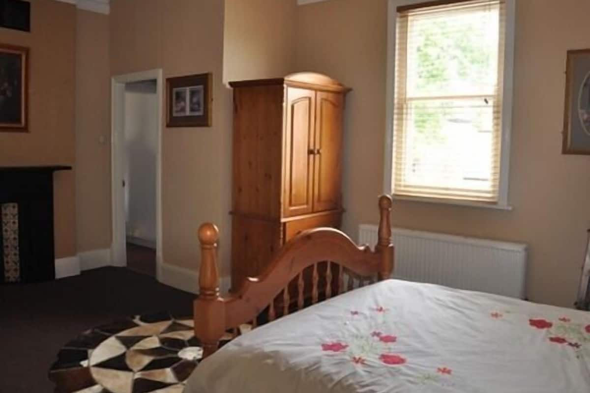 A bedroom with a wooden bed, a large window, and a cabinet.