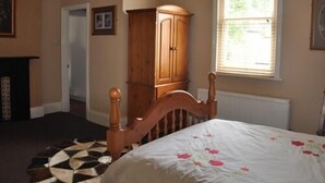 A bedroom with a wooden bed, a large window, and a wooden cabinet. - The Locomotion Hotel (Stockton-on-Tees)