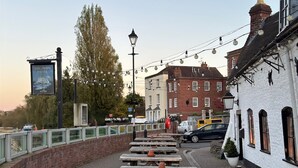 A riverside walkway with wooden benches and a sign for The Swan Hotel. - The Swan Hotel (Worcester)