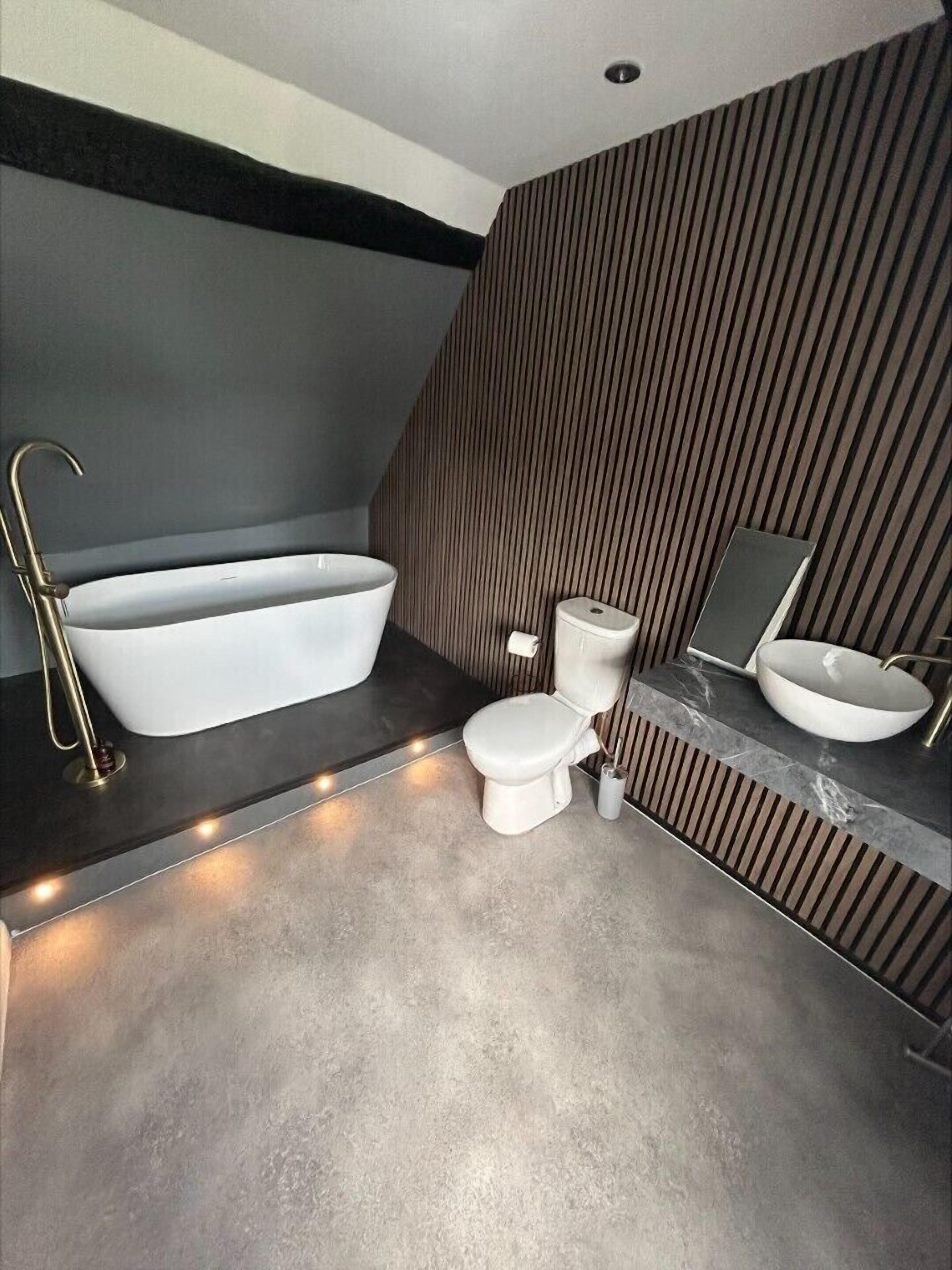 Une salle de bain moderne avec une baignoire sur pieds, des toilettes et un meuble-lavabo avec un évier.