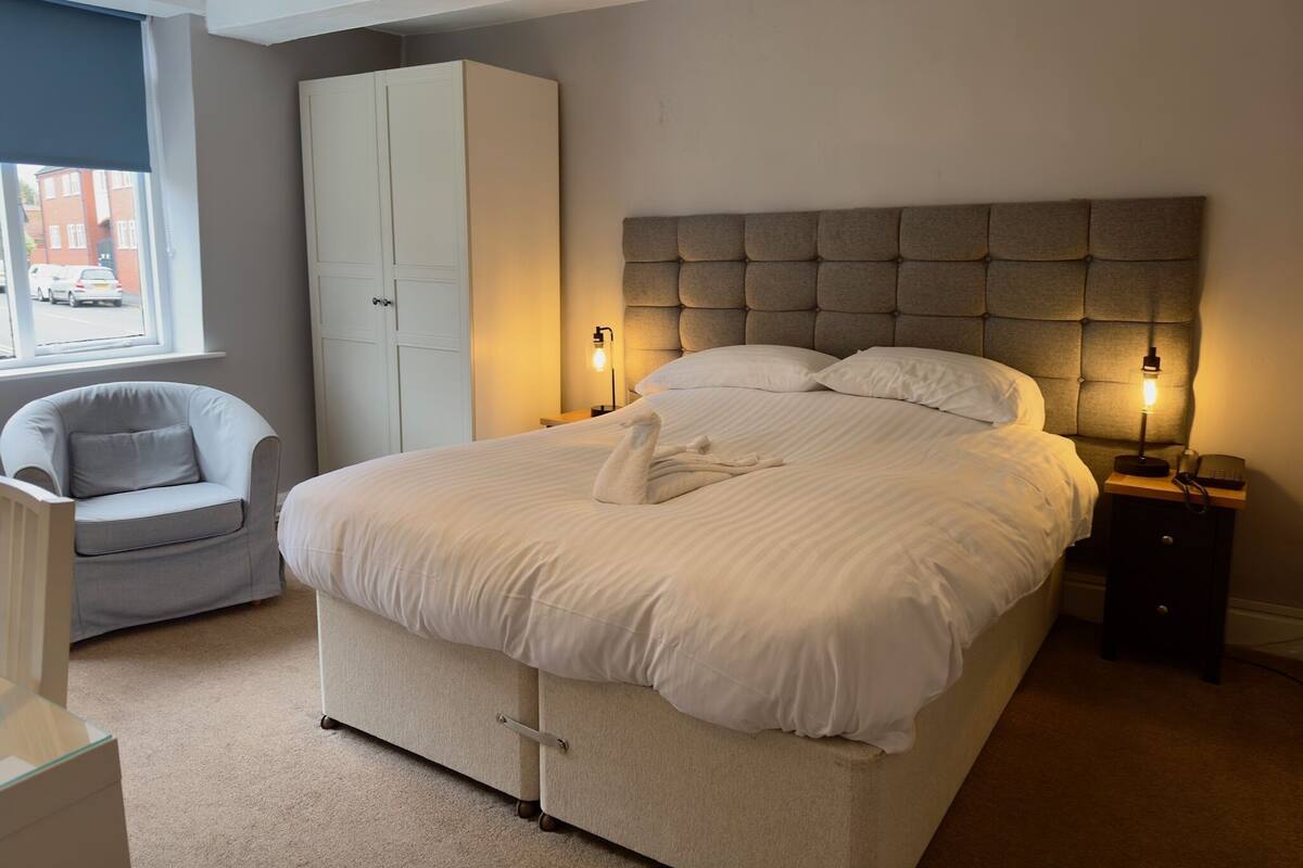Quarto com uma cama grande, um guarda-roupa, uma cadeira e abajures.