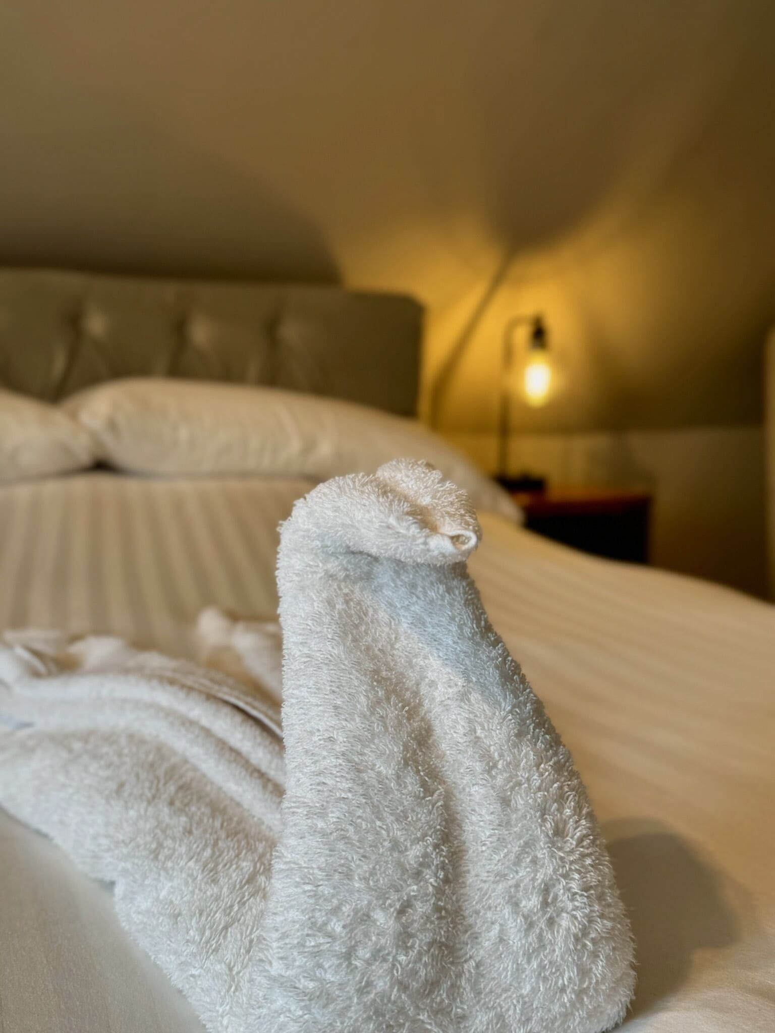 A neatly made bed with a white towel folded on top.