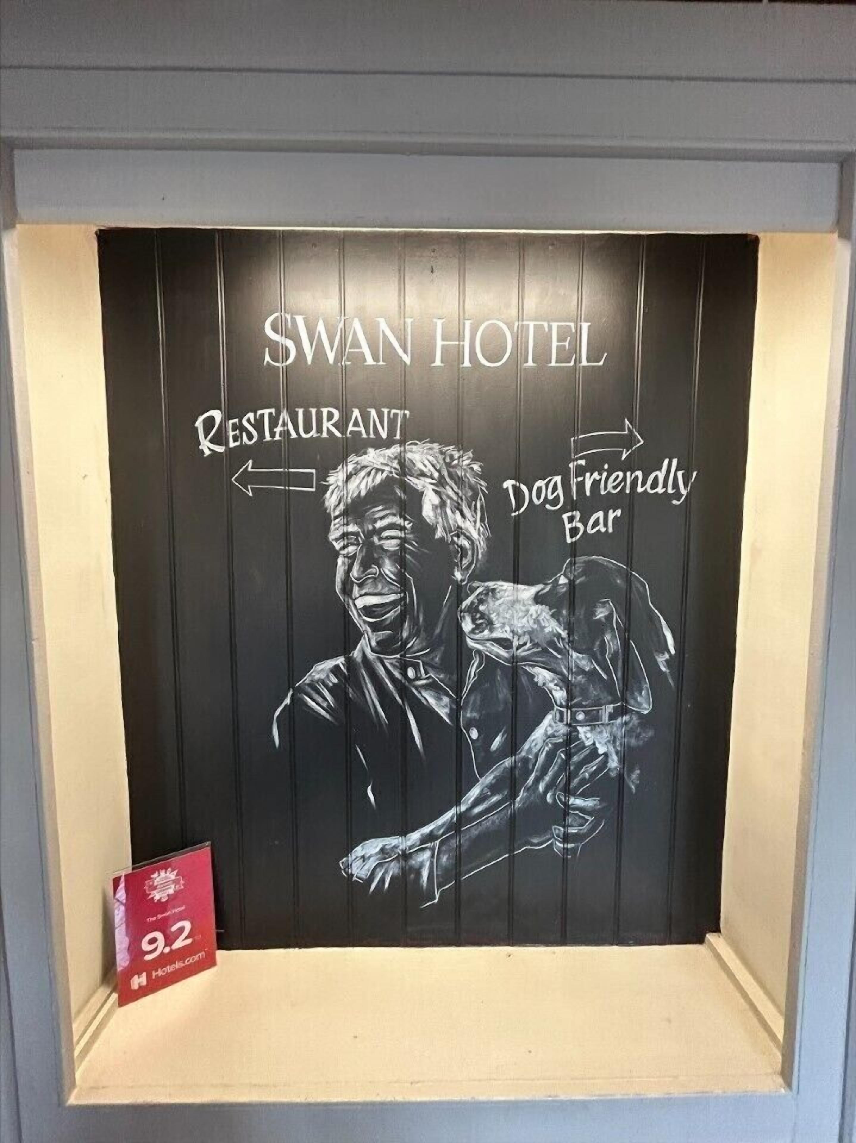 A blackboard with 'SWAN HOTEL' and directional signs to 'RESTAURANT' and 'Dog Friendly Bar'.