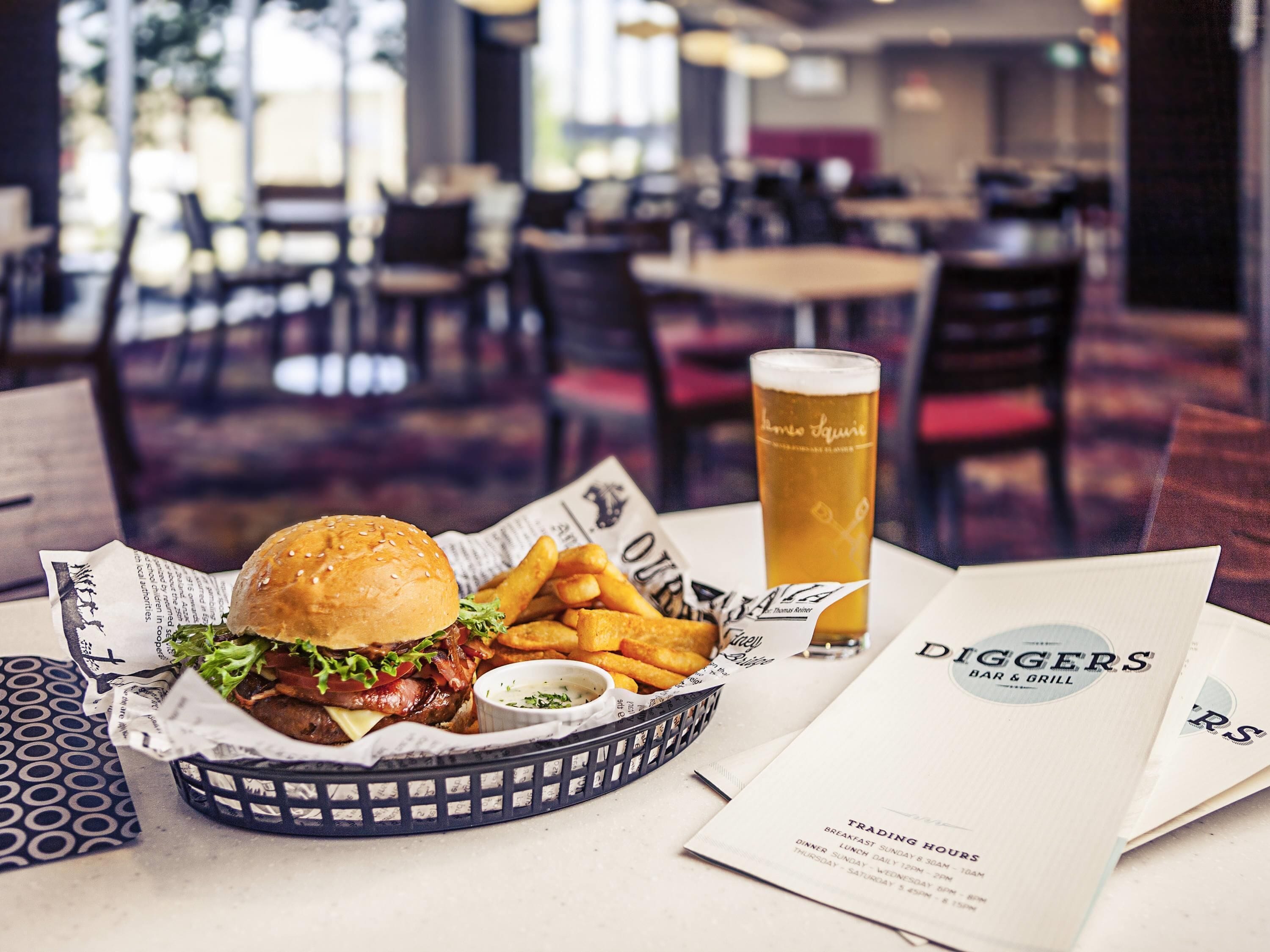 A meal with a burger, fries, and a beer glass, along with a menu and a sign for a bar and grill.