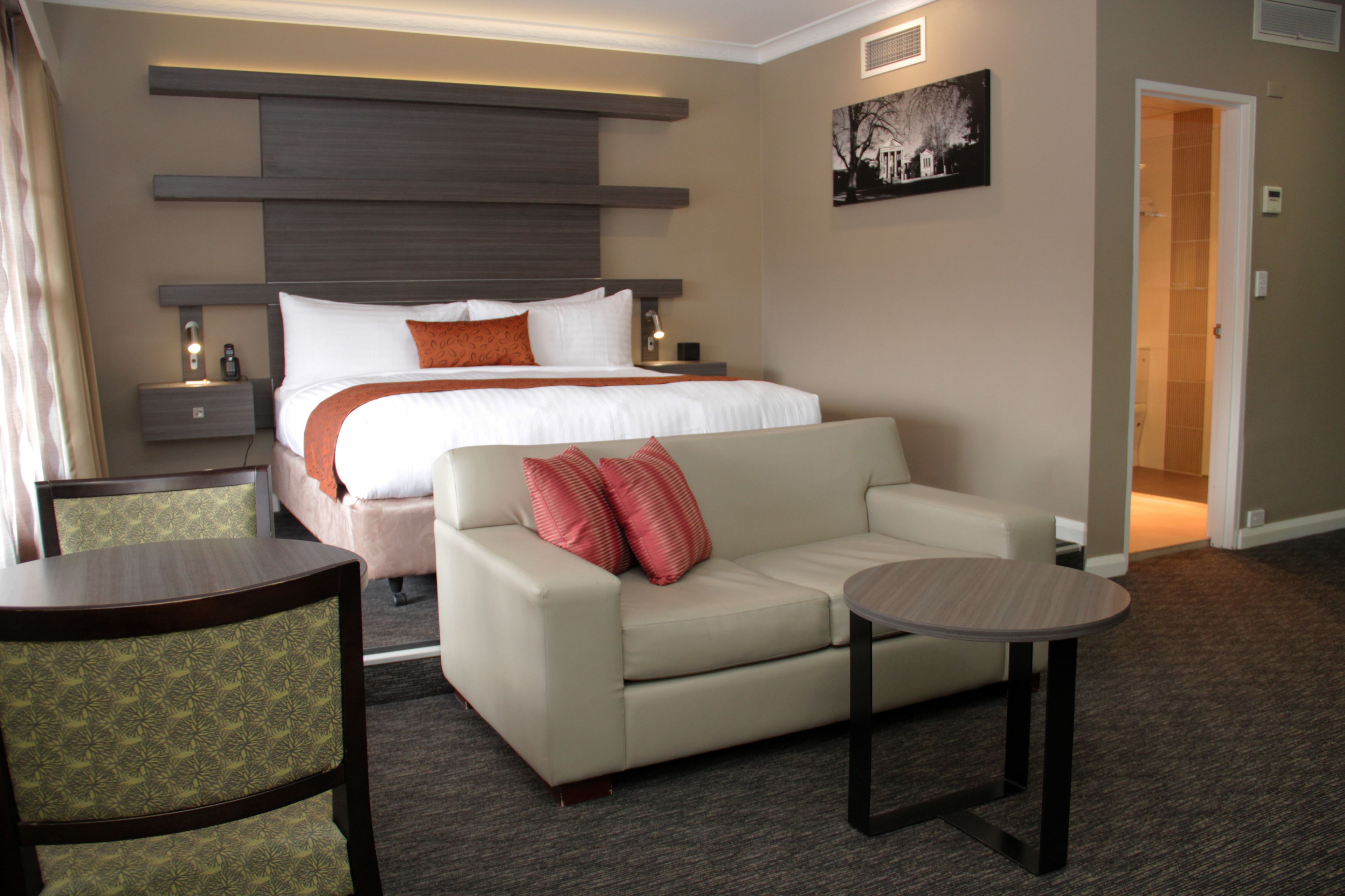 Una habitación de hotel con una cama, un sofá, una mesita y una silla.