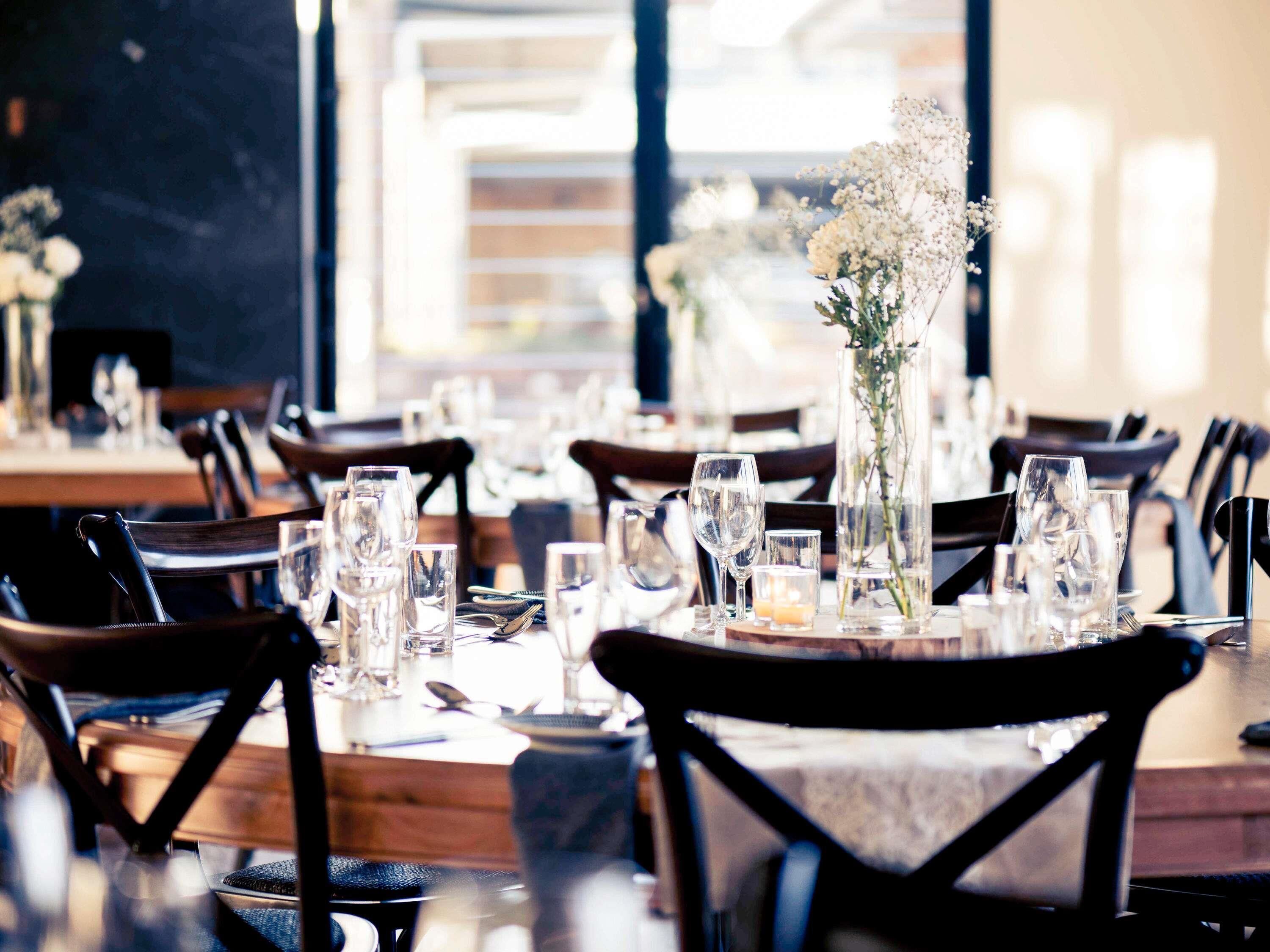 A restaurant with tables set for dining, featuring clear glassware and floral centerpieces.