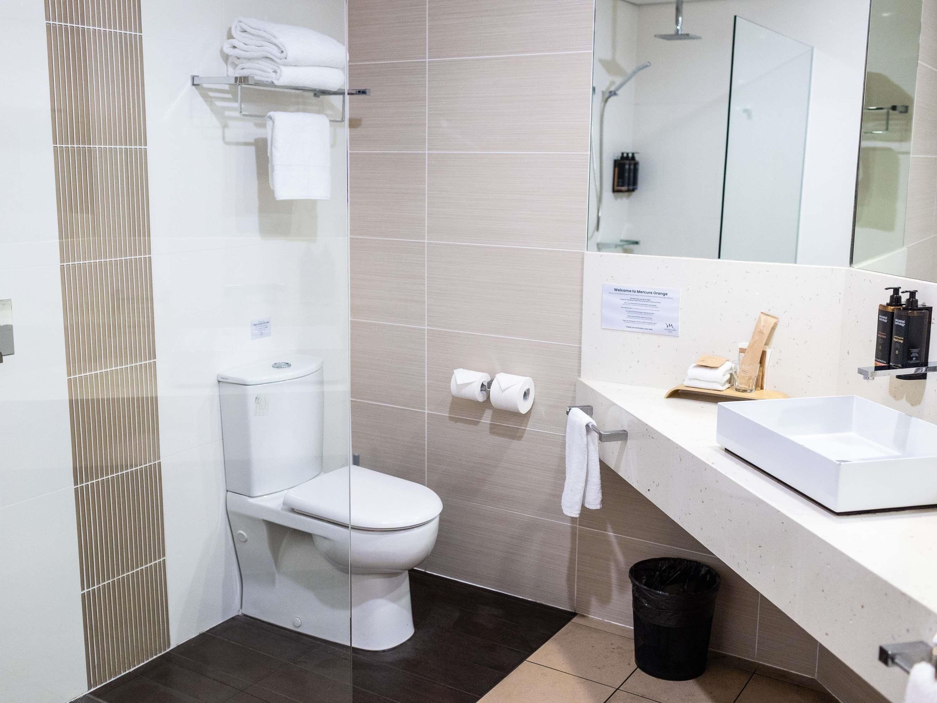 Un baño moderno con inodoro, lavabo y espejo.
