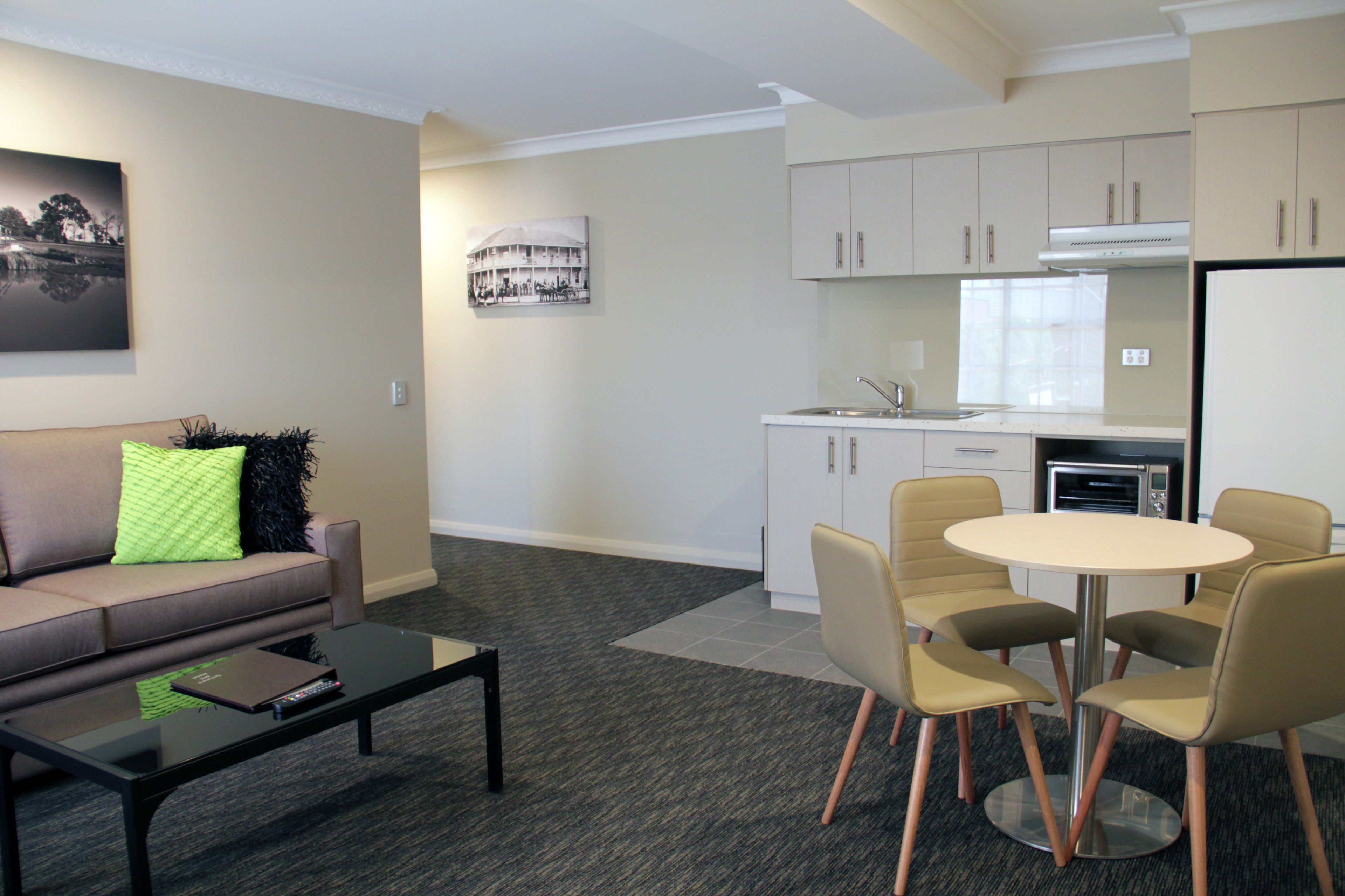 A modern living room with a sofa, coffee table, and a dining area with chairs and a table.