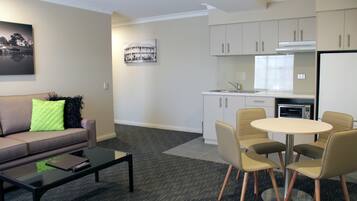 A modern living room with a sofa, coffee table, and a dining area with chairs and a table.