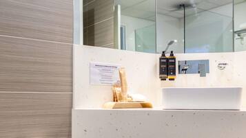 A modern bathroom with a white sink, two toiletries, a towel, and a welcome sign.
