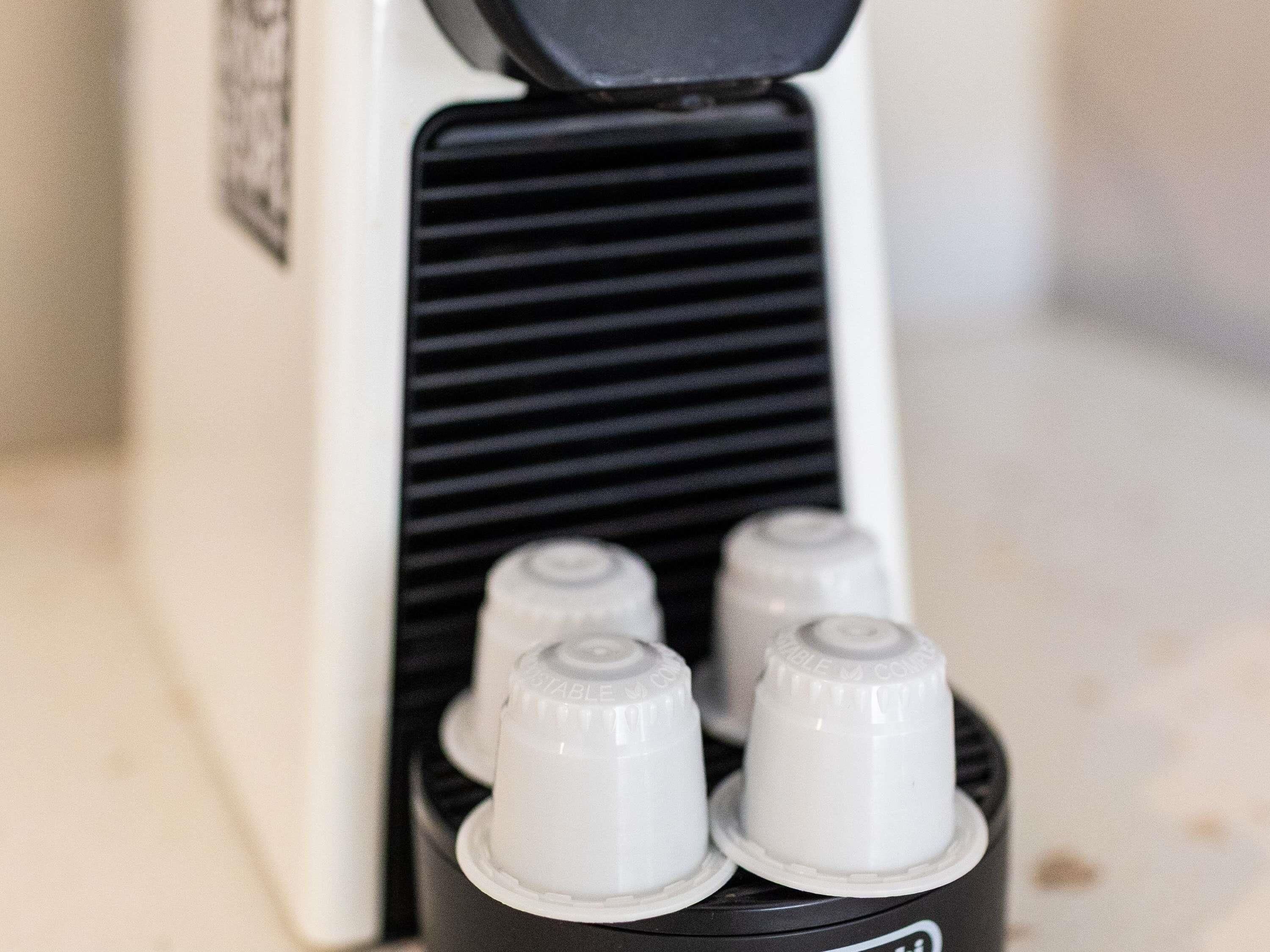 Eine Kaffeemaschine mit vier weißen Tassen und einer schwarzen Bedieneinheit.