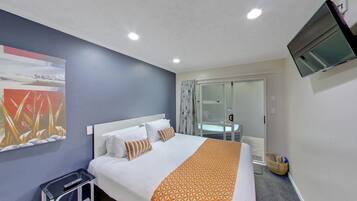 A hotel room with a bed, a TV mounted on the wall, and a window with curtains.