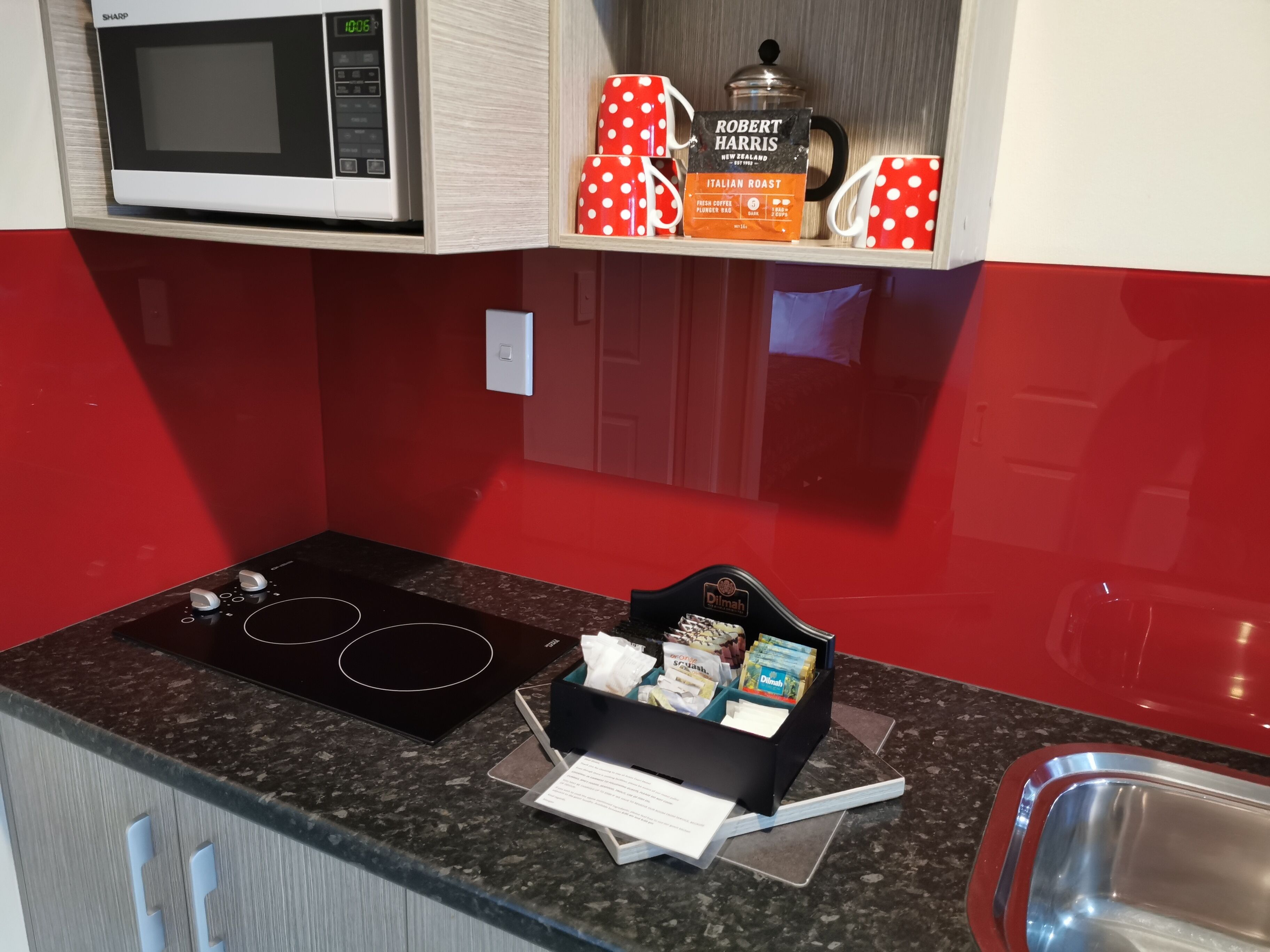 Una cocina compacta con microondas, cafetera y hervidor sobre la encimera.