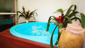 Une petite piscine intérieure aux parois bleues, entourée de plantes en pot et d’un panier en osier.