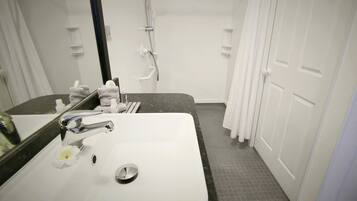 A bathroom with a white sink, a mirror, a towel rack, and a shower area.