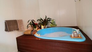 Une salle de bain avec une baignoire bleue, un banc en bois, un porte-serviettes et une plante en pot.