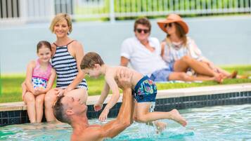 A swimming pool with a family enjoying the water.