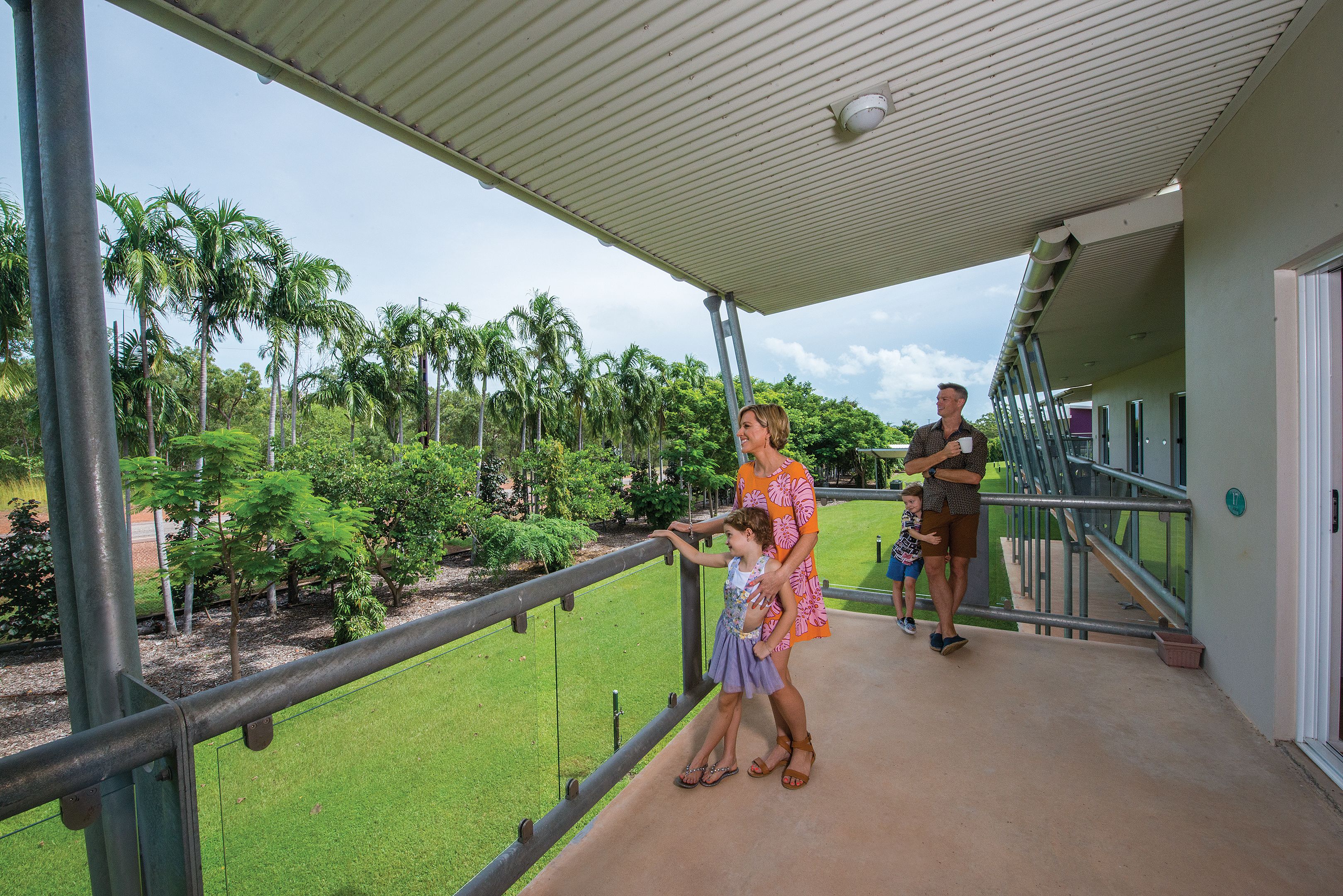 A balcony with a view of palm trees and a grassy area.