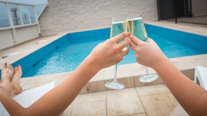 Dos personas brindando con copas de champán junto a una piscina.