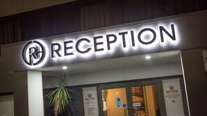 Una recepción de hotel con un letrero que dice "RECEPTION" y un logotipo con "RH".