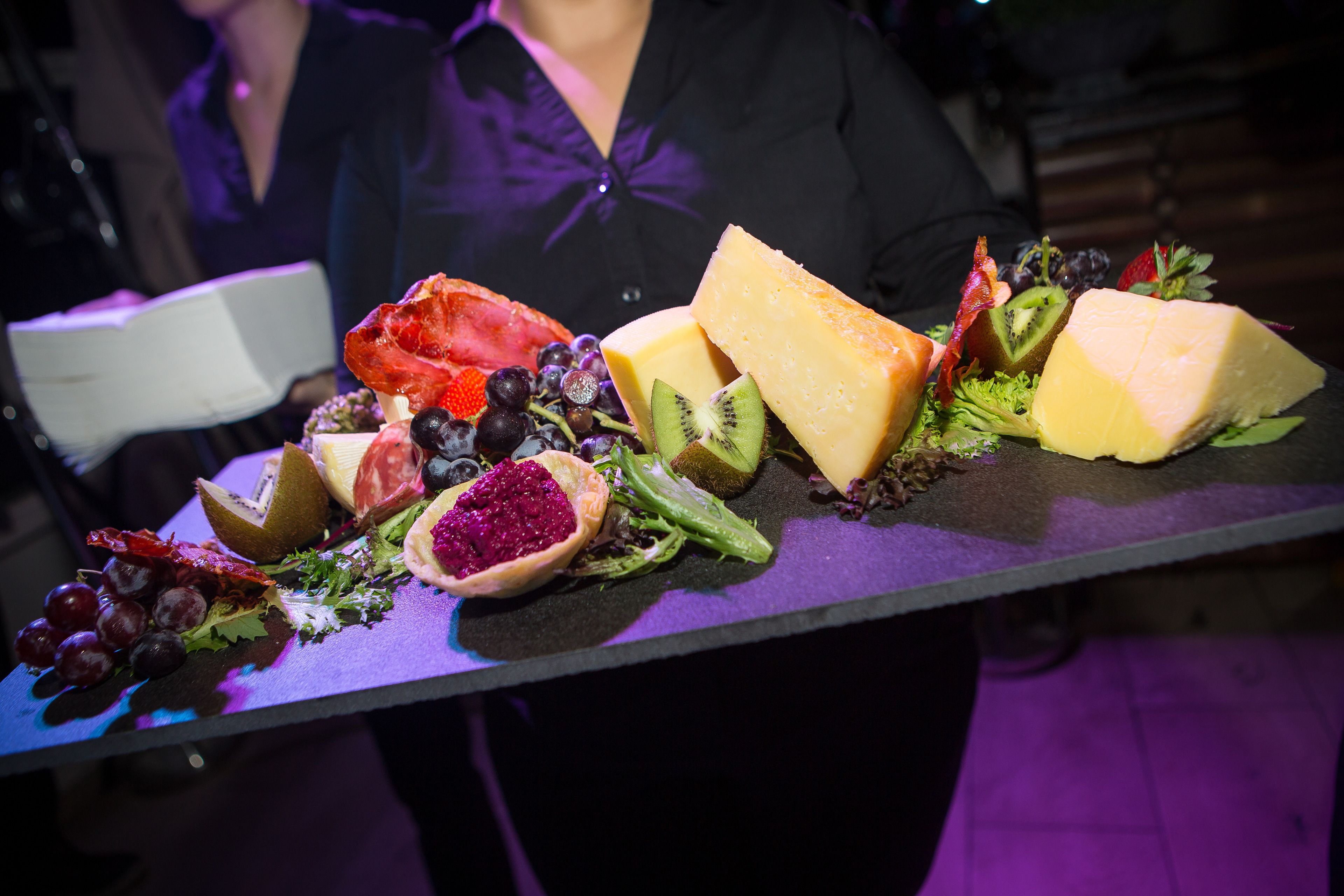 Un plateau garni de fromages et de fruits variés, posé sur une table.
