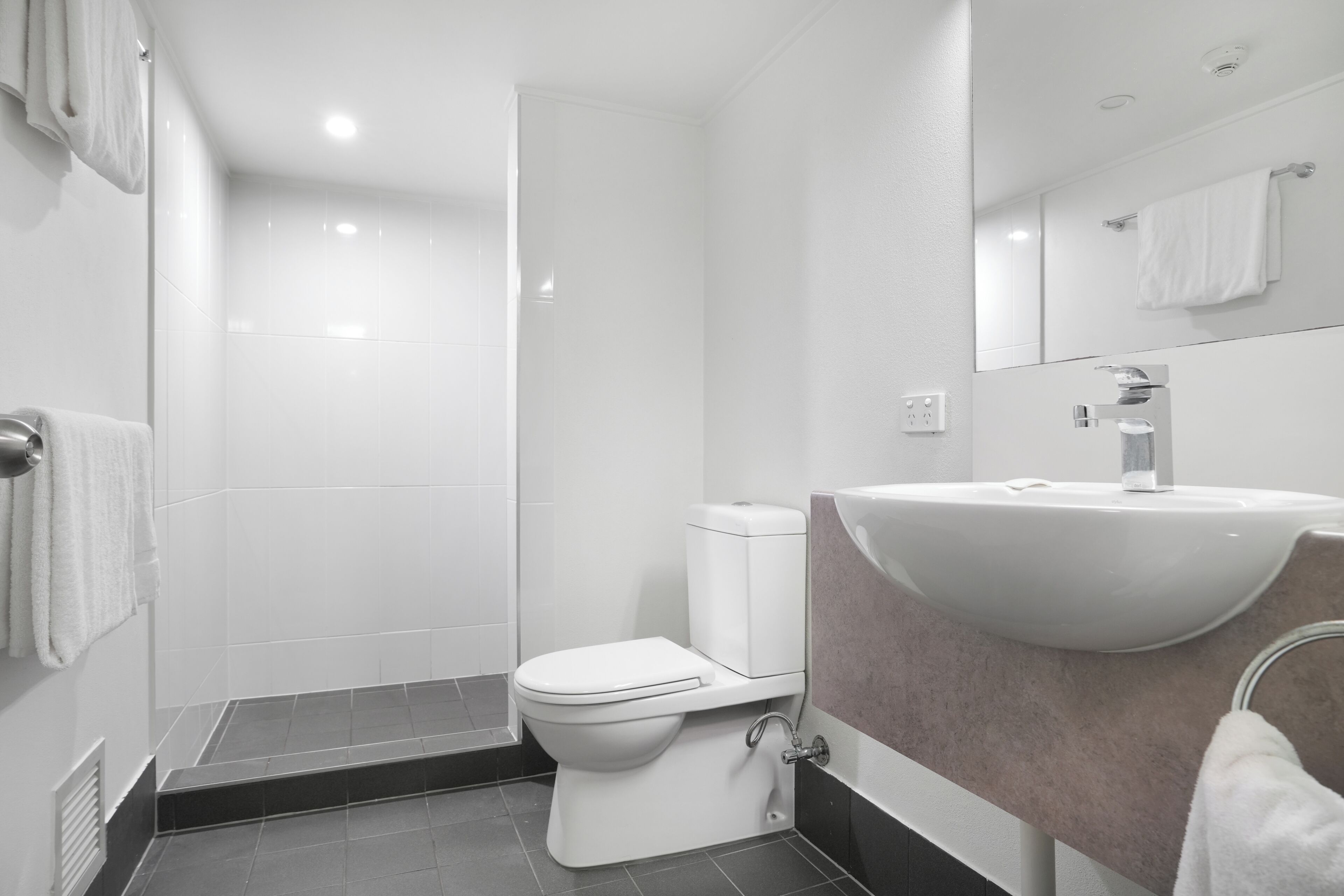 Une salle de bain moderne équipée de toilettes, d’un lavabo et d’une douche.