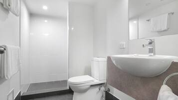 Un baño moderno con inodoro, lavamanos y ducha.