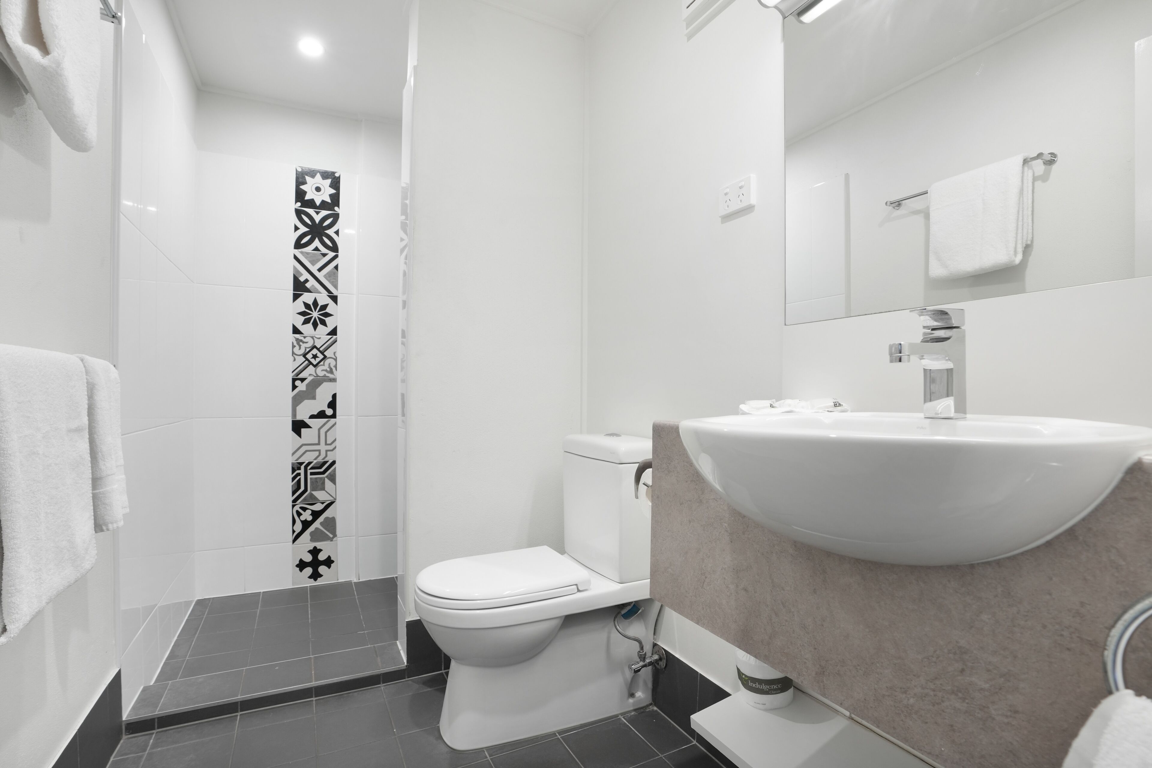 A modern bathroom with a white sink, toilet, and shower.