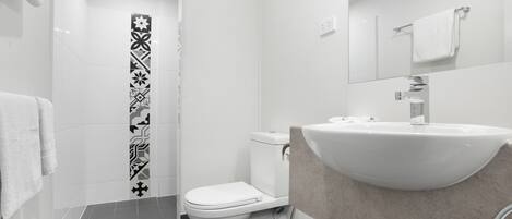 A modern bathroom with a white sink, toilet, and shower.