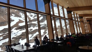 Un restaurant doté de grandes fenêtres donnant sur un paysage montagneux enneigé.