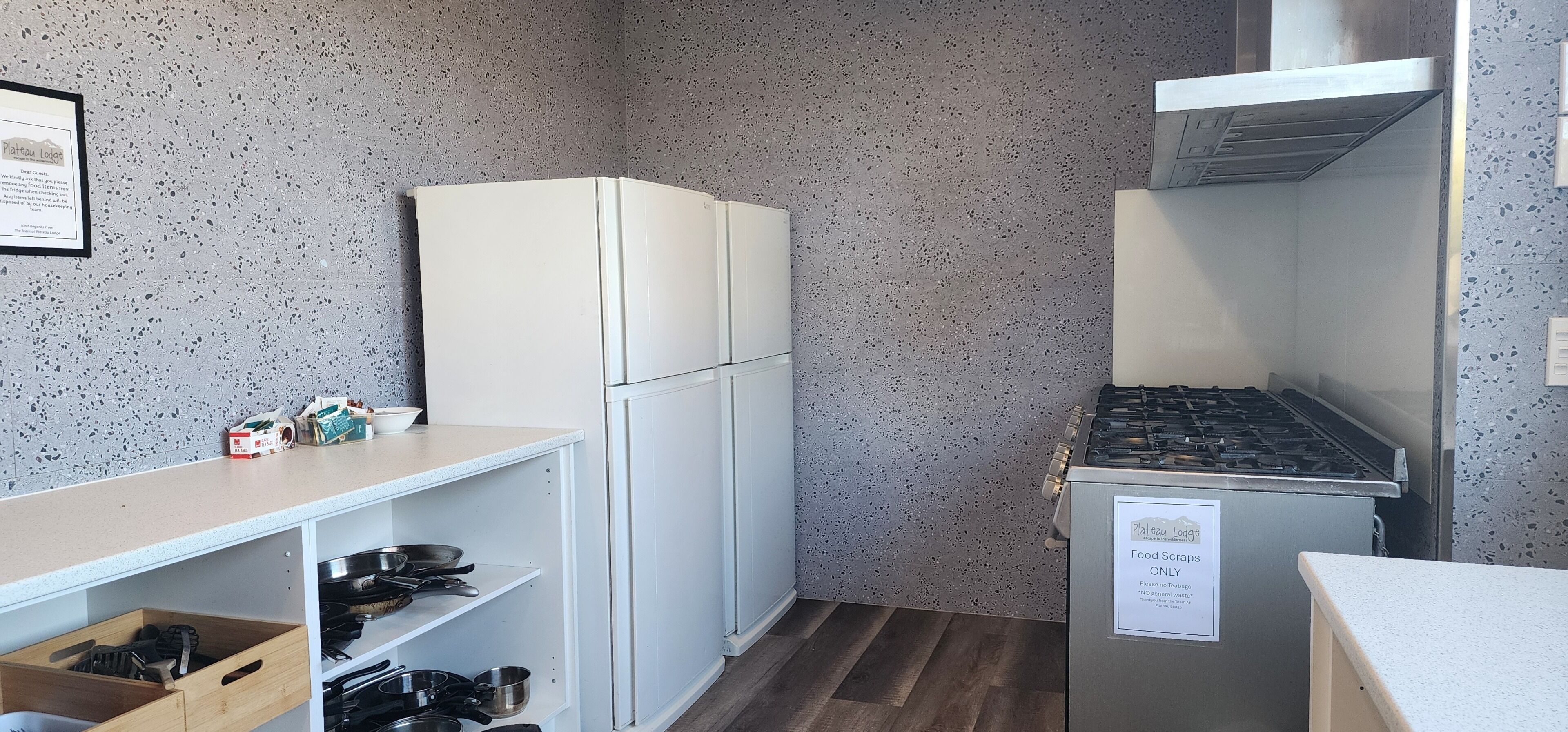 A kitchenette with a white refrigerator, a stove, and a sign indicating food scraps only.