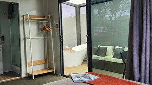 Une pièce dotée d’une porte vitrée donnant sur un balcon aménagé avec un canapé et des coussins.