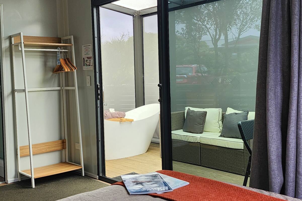 A room with a glass door leading to a balcony with a sofa and cushions.