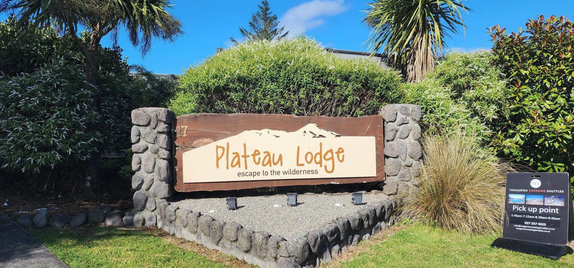 A sign for Plateau Lodge with a mountainous backdrop.