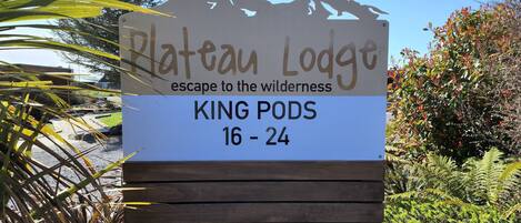 Letrero de Plateau Lodge publicitando una escapada a la naturaleza, con habitaciones tipo King Pods para mayores de 16 a 24 años.