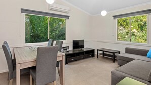 Una sala de estar moderna con una mesa de comedor, sofás grises y un televisor.