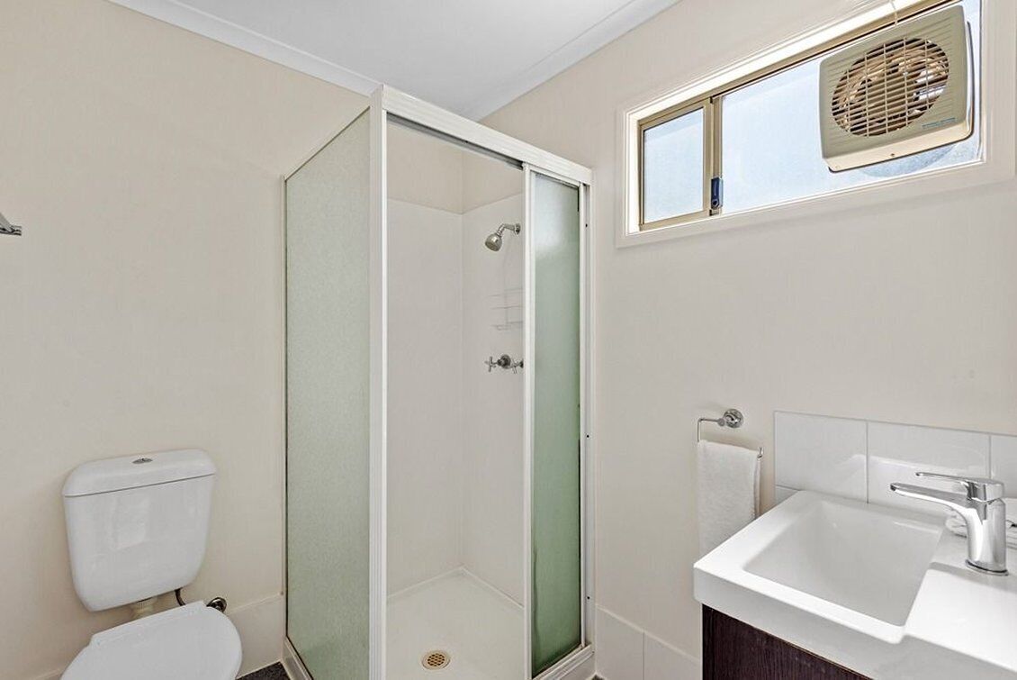 Een badkamer met een douche met glazen wand, een toilet en een wastafel met spiegel erboven.