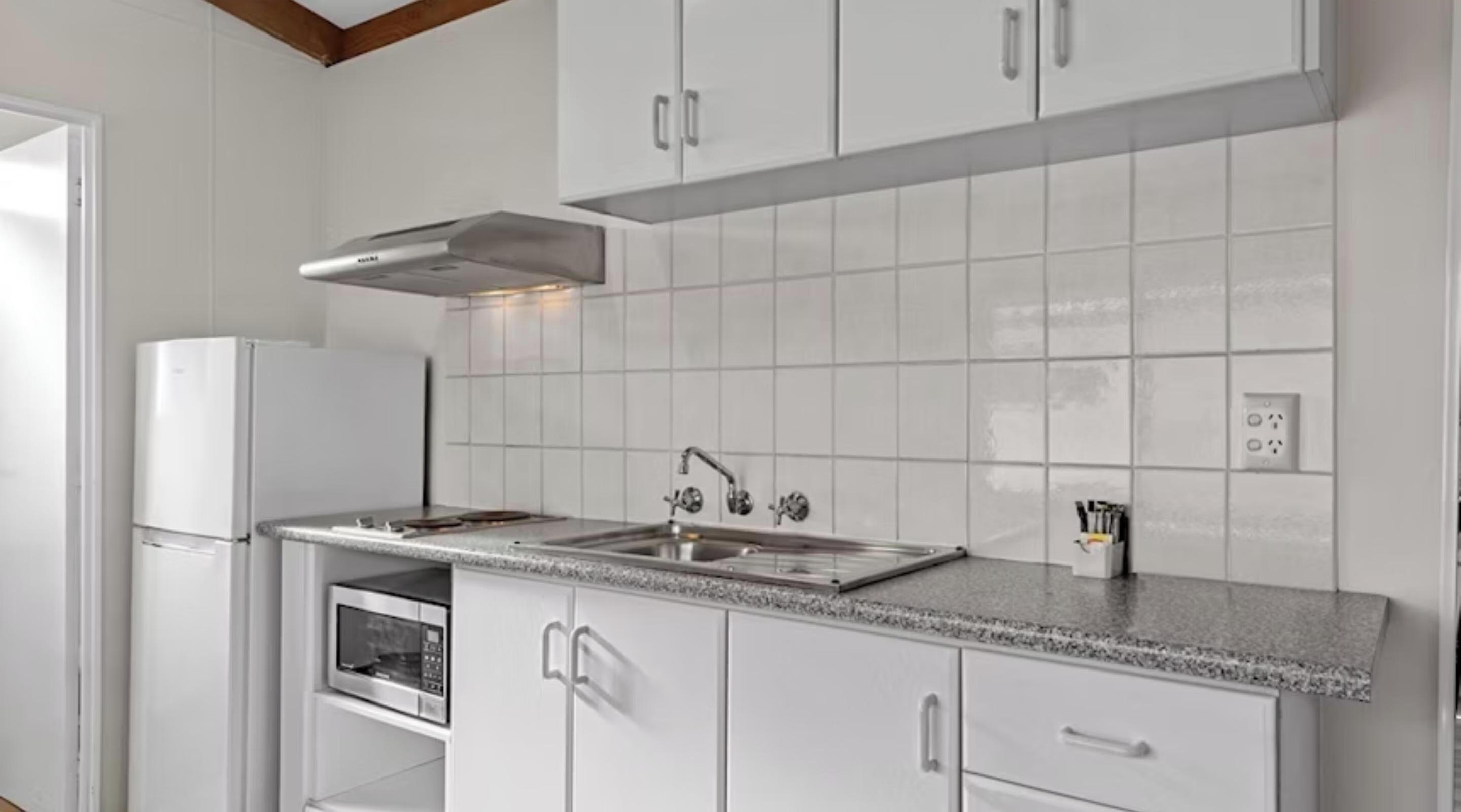 A modern kitchen with white cabinets, a stainless steel sink, and a built-in microwave.