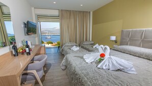 A hotel room with a bed, a desk with a chair, a TV, and a view of the sea. - Paradise Lost Hotel-Apartments (Nafplio)