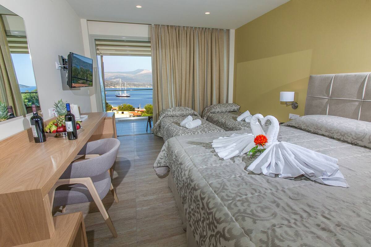 Hotelkamer met een bed, een bureau met stoel, een televisie en uitzicht op zee.