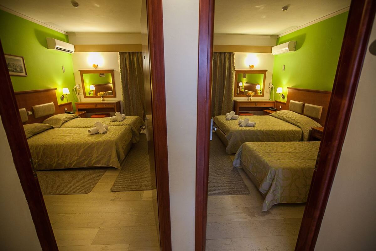 Een hotelkamer met twee bedden, een houten hoofdbord, een spiegel, een nachtkastje en een lamp.