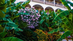 A hotel with multiple balconies, lush greenery, and flowering plants. - Paradise Lost Hotel-Apartments (Nafplio)