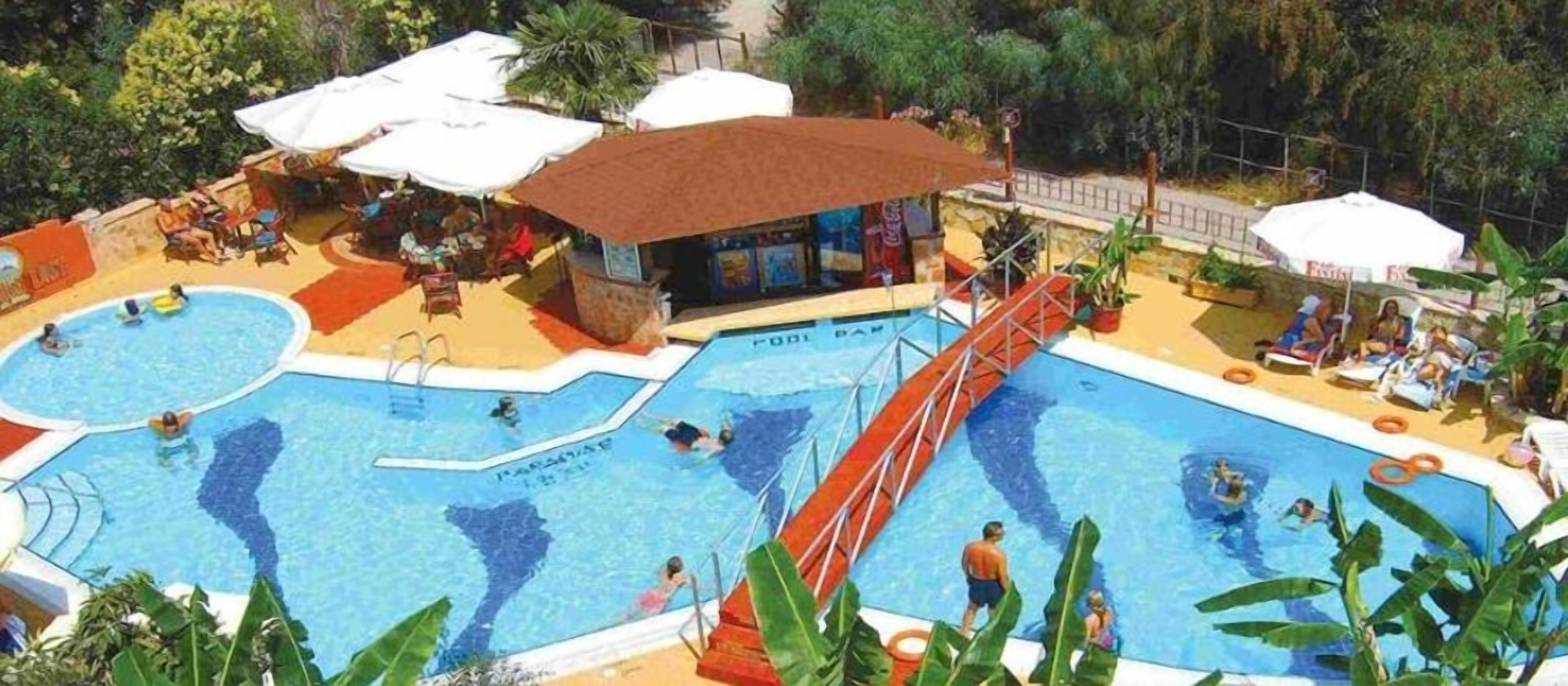 An outdoor swimming pool with multiple lanes, a red slide, and lounge areas with umbrellas.